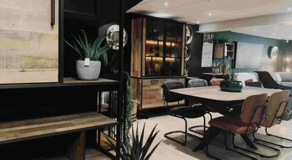 Een sfeervolle woonkamer met een **donker hout keuken** element, een eettafel met stoelen en planten.