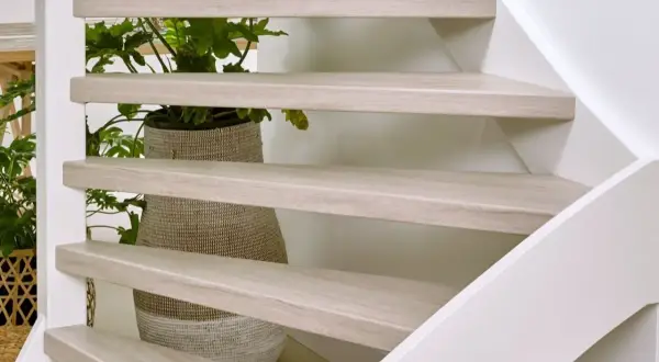 Lichte houten traptreden met planten erachter. Inspiratie voor open trap opknappen ideeën.
