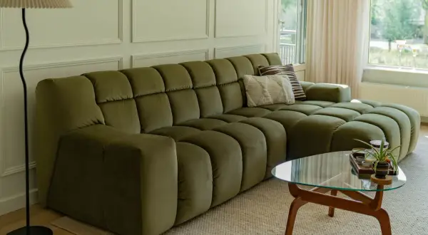 Een olijfgroene bank met zachte kussens, de perfecte basis. Welke kleur past bij groene bank? Denk aan warme aardetinten of frisse pastels voor een harmonieus interieur.