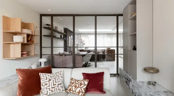 Moderne woonkamer met glazen wand, houten wandrek en comfortabele bank. Een nis in de muur is stijlvol ingericht.