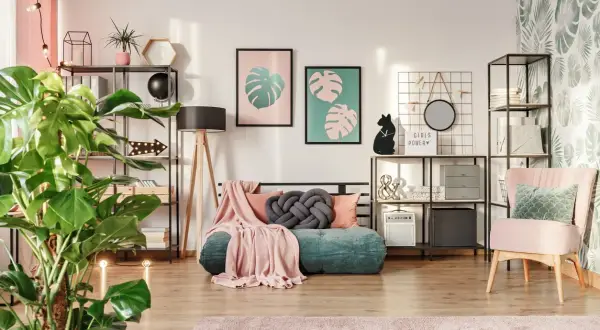 Een gezellige kamer waar groen en roze combineren interieur. Een groene bank met roze plaids, planten en decoratie.