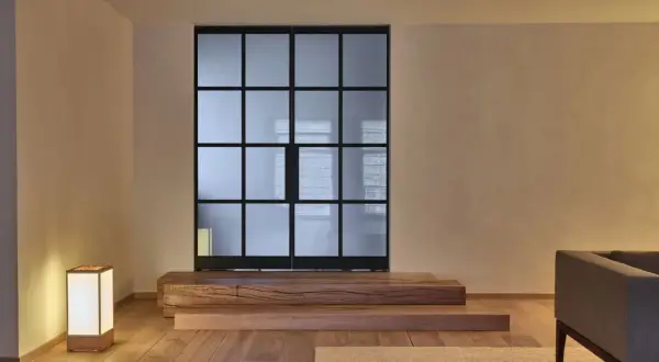 Een serene woonkamer met een glazen scheidingswand, houten elementen en een lamp, die de essentie van Japans minimalisme uitstraalt.