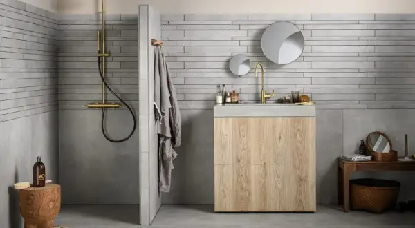 Grijze badkamer met houten meubel. Welke kleur handdoeken passen hierbij? Een grijze handdoek hangt aan de muur.