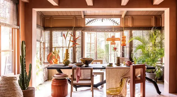 Warme, aardse tinten domineren deze eetkamer. De balken van het plafond zijn geschilderd in een lichte kleur, wat een mooi contrast vormt met de terracotta muren.