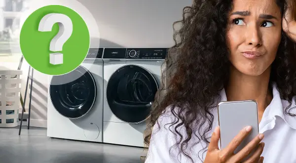 Vrouw met telefoon kijkt gefrustreerd naar wasmachine. Is er te weinig was in wasmachine?