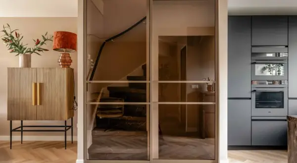 Moderne glazen schuifdeuren geven trapgat inspiratie. Een marmeren trap met donkere treden en een houten vloer.