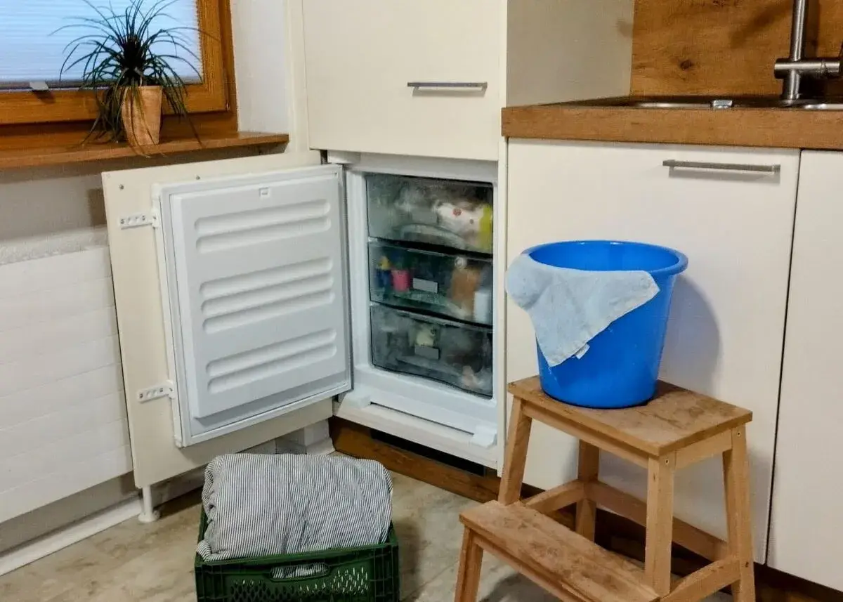 Vriezer niet goed dicht gedaan, met een blauwe emmer en doek klaar voor de ontdooiing.