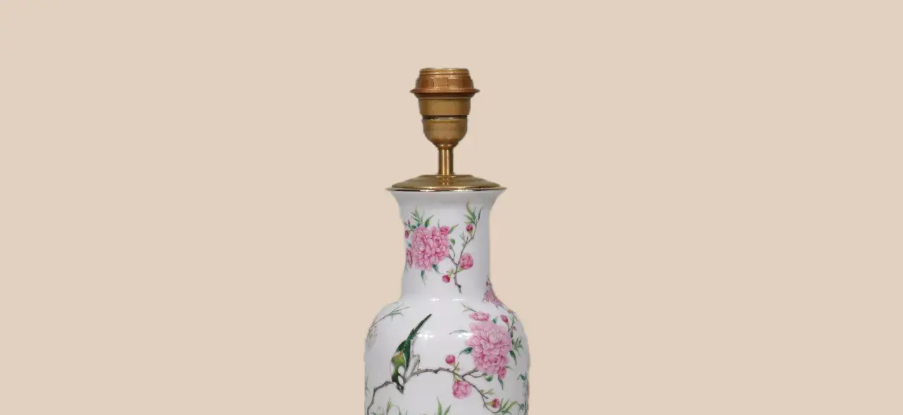 Een lamp maken van vaas: een witte vaas met roze bloemen en een vogel, omgebouwd tot lamp met een gouden fitting.
