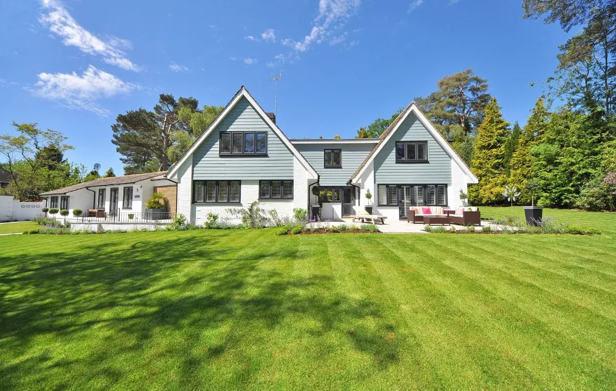 Een ruime woning met een aangebouwde garage, omringd door een perfect gemaaid gazon en bomen. Dit is een voorbeeld van wat een kangoeroewoning kan zijn: een woning met een apart woongedeelte.