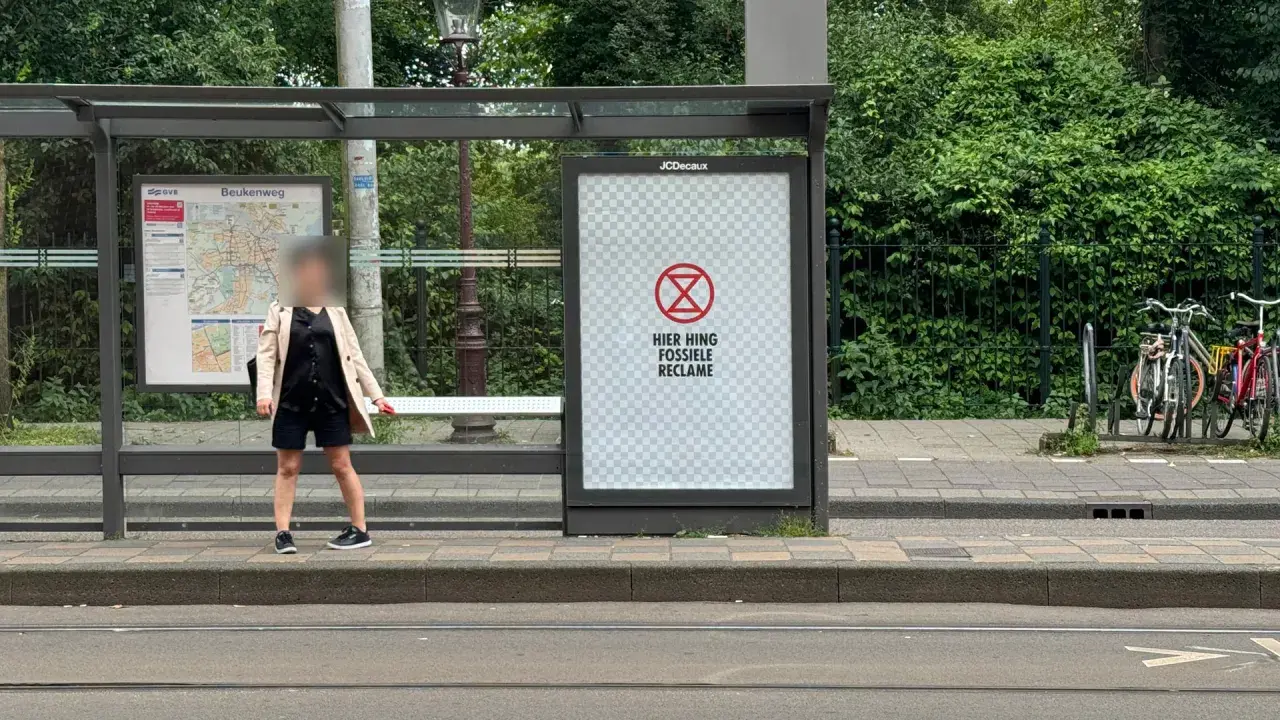 Een poster bij een bushalte met een symbool en de tekst "HIER HING FOSSIELE RECLAME". Dit is een oproep om geadresseerde reclame stopzetten.