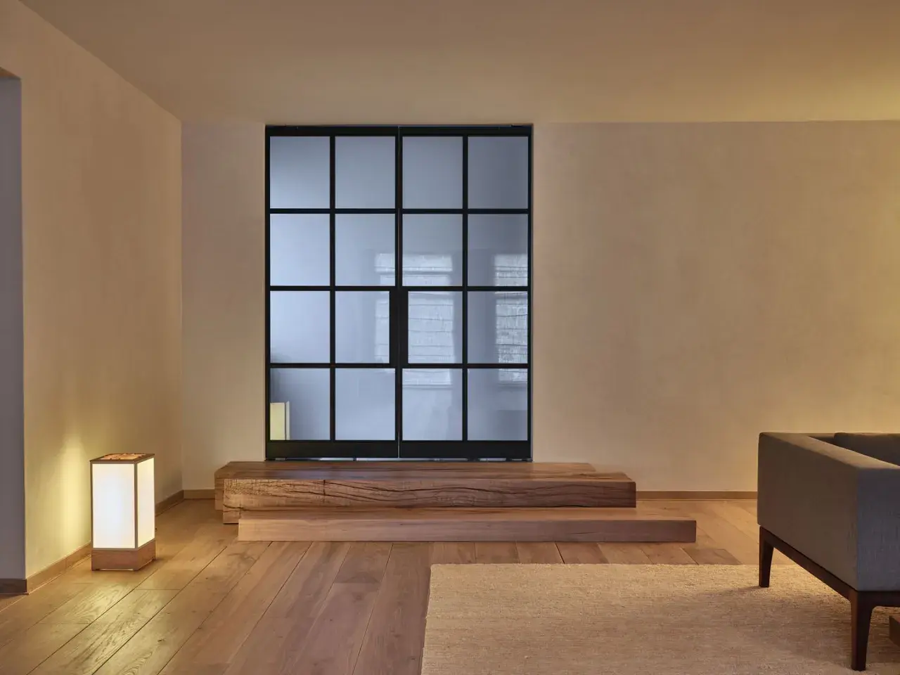 Een serene woonkamer met een glazen scheidingswand, houten elementen en een lamp, die de essentie van Japans minimalisme uitstraalt.
