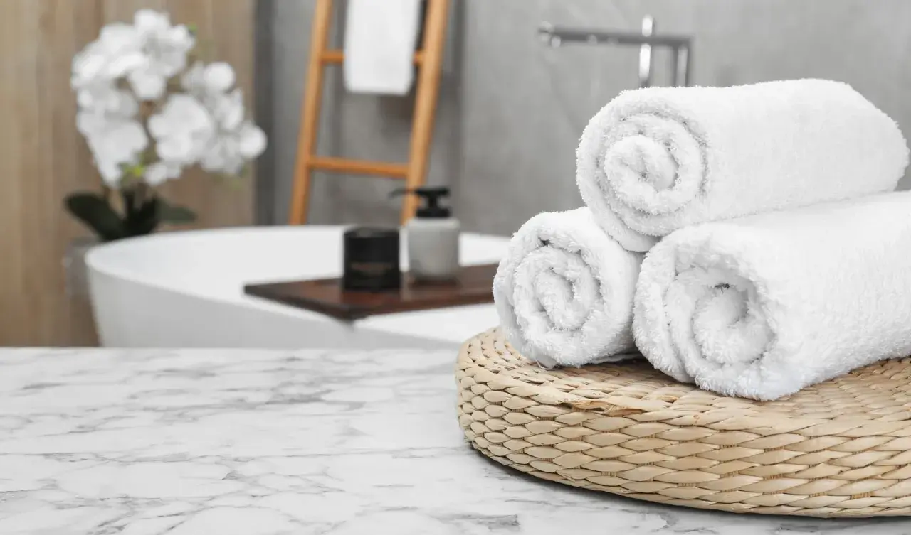 Frisse, witte handdoeken, net gewassen, liggen op een mandje in een luxe badkamer.