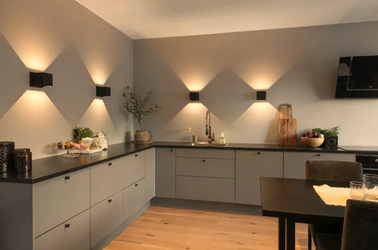 Moderne keuken met sfeervolle keuken verlichting inspiratie. Zwarte wandlampen creëren een prachtig lichtspel op de grijze muur.
