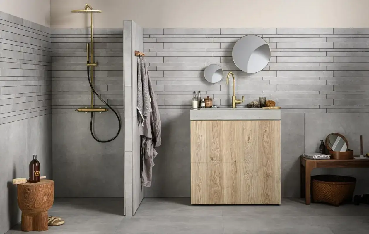 Grijze badkamer met houten meubel. Welke kleur handdoeken passen hierbij? Denk aan taupe of donkergrijs voor een rustige look.