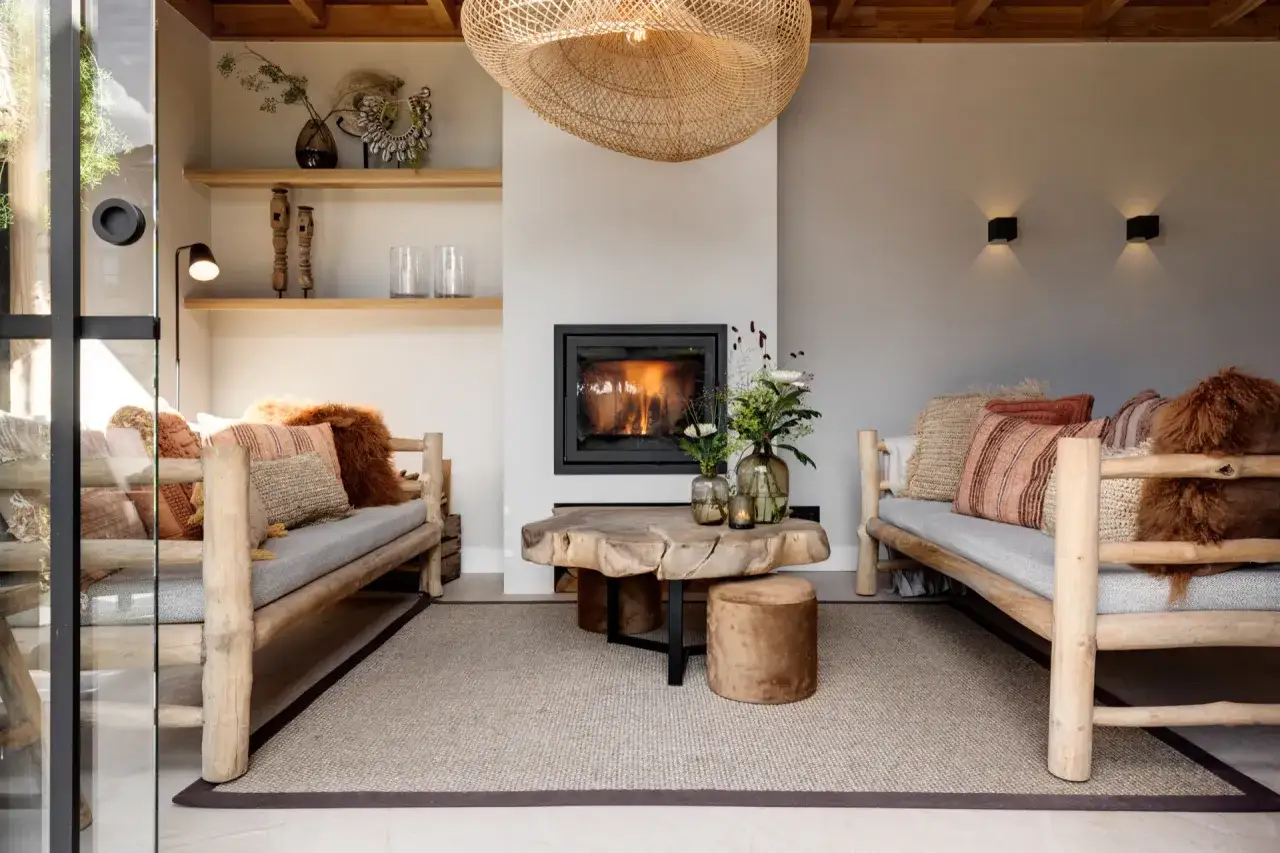 Gezellige toog woonkamer met open haard, houten meubels en warme kussens.