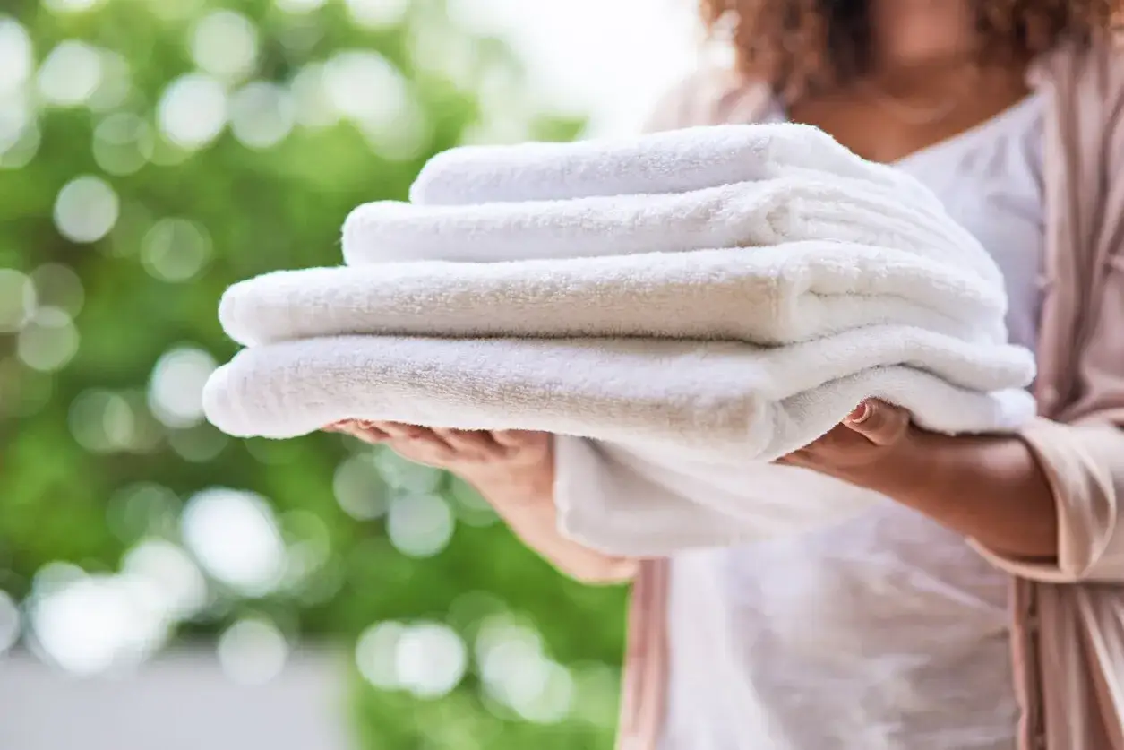 Een stapel schone, witte handdoeken wordt vastgehouden, klaar om opgevouwen te worden na het wassen.