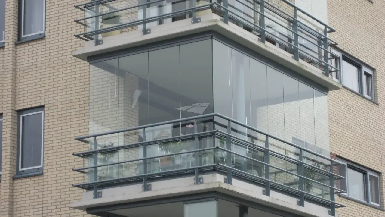 Moderne glazen schuifwanden maken dit balkon dicht, waardoor het een extra leefruimte wordt.