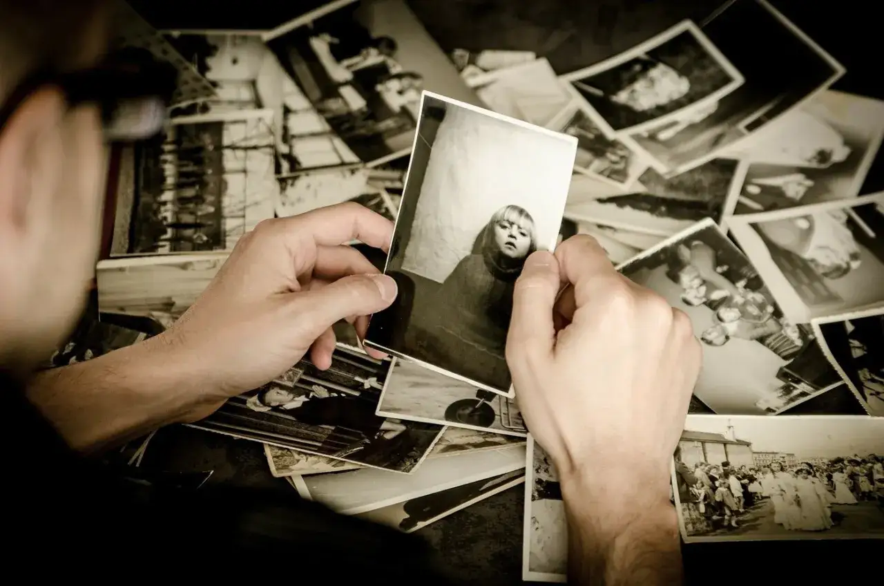 Een persoon bekijkt oude zwart-witfoto's, een nostalgische reis door het verleden. Wat te doen met oude foto's? Deze beelden roepen herinneringen op.