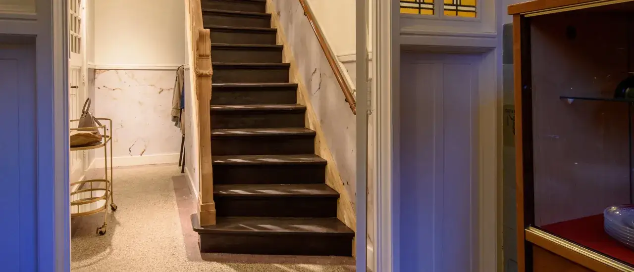 Donkere trap in de vestibule woning, met marmeren accenten en een gouden serveerkar.
