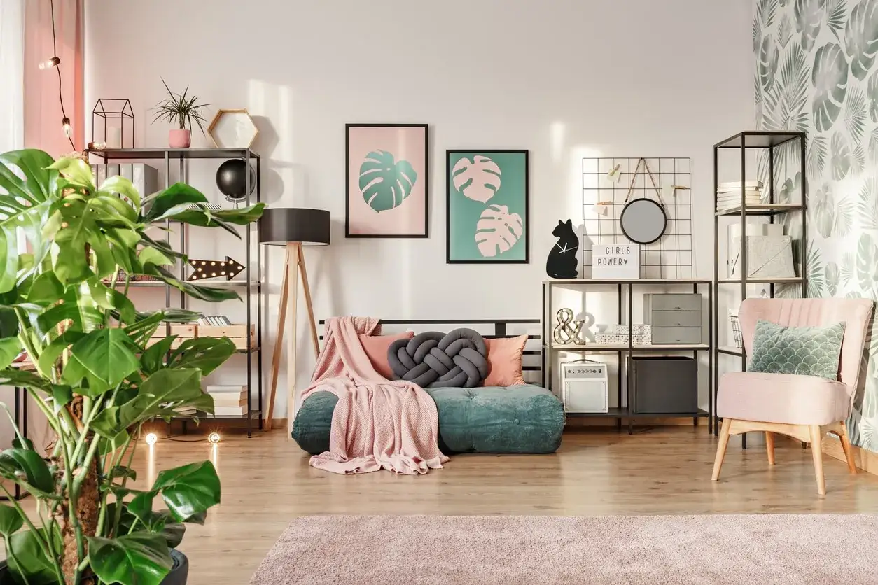 Een gezellige kamer waar groen en roze combineren interieur. Een groene bank met roze plaids, planten en decoratie.