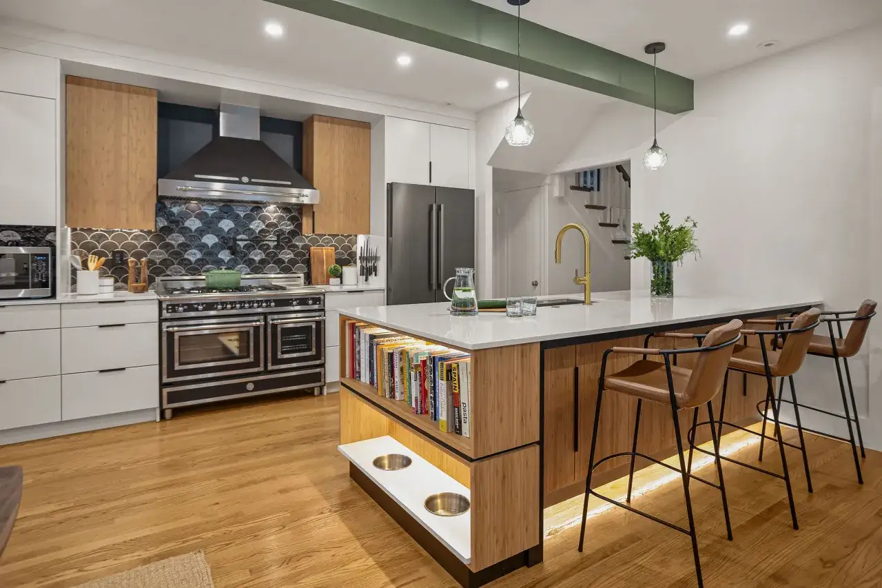 Moderne keuken met eiland, gouden kraan en sfeervolle keuken verlichting inspiratie. Boekenplank en hondenbakjes ge&iuml;ntegreerd.