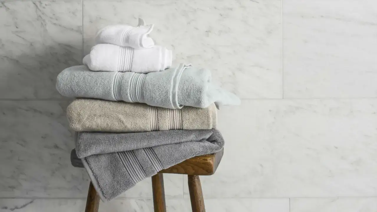 Stapel zacht opgerolde handdoeken in verschillende kleuren, klaar voor gebruik in de badkamer.