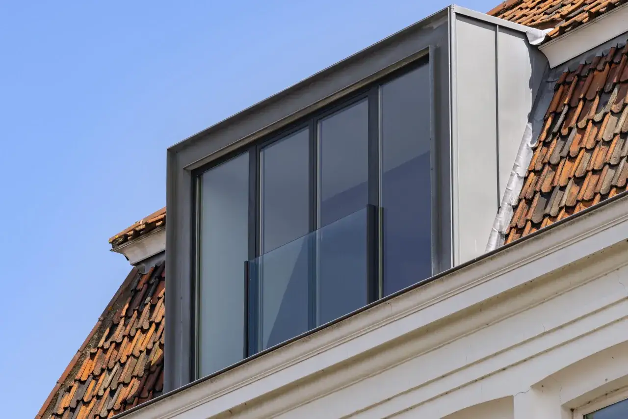 Moderne dakkapel met grote ramen, een glazen balustrade en zinken afwerking. Dit toont aan wat is prefab: een effici&euml;nte bouwmethode.