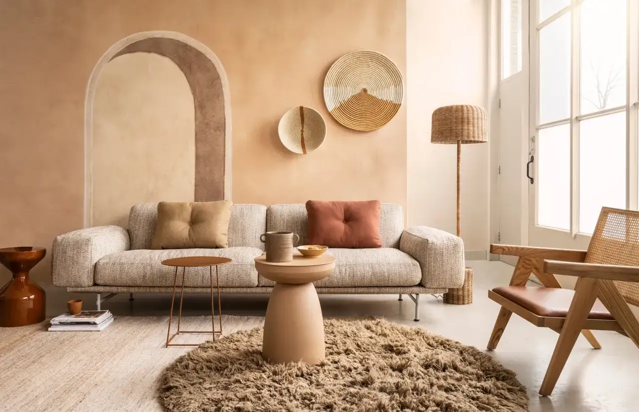 Gezellige woonkamer met bank, fauteuil en een muur met een subtiele ombre effect.