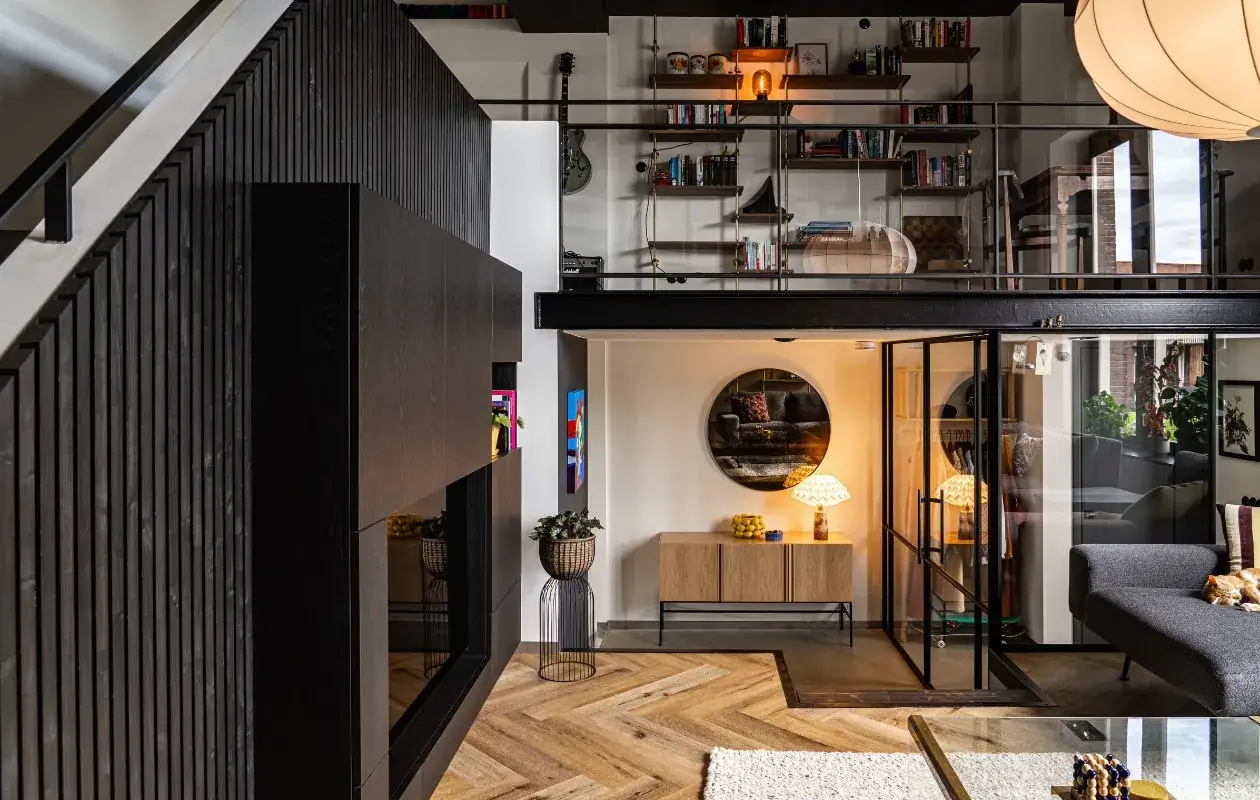Modern interior with a black slatted wall, mezzanine, glass-enclosed room, and herringbone floor.