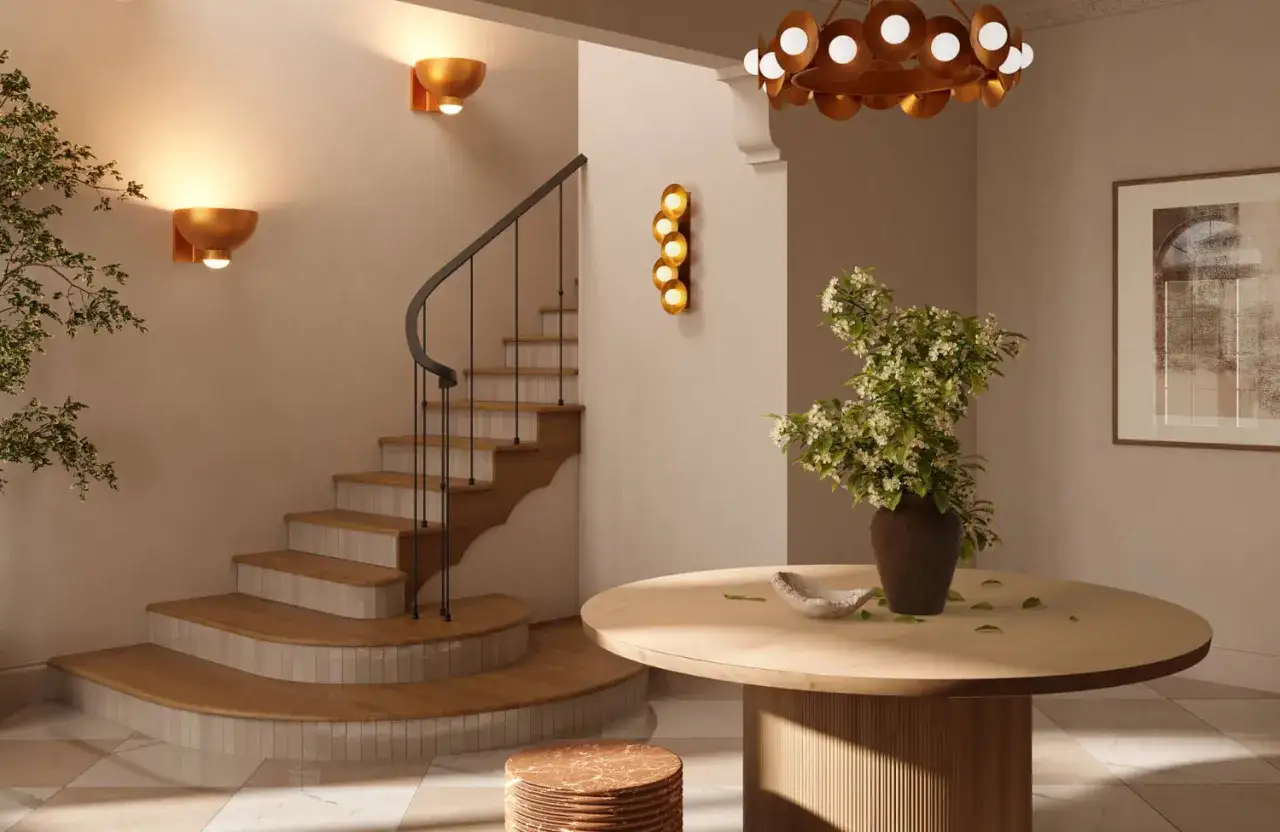 Een mooie hal met een houten trap, een ronde tafel met bloemen en een opvallende kroonluchter.