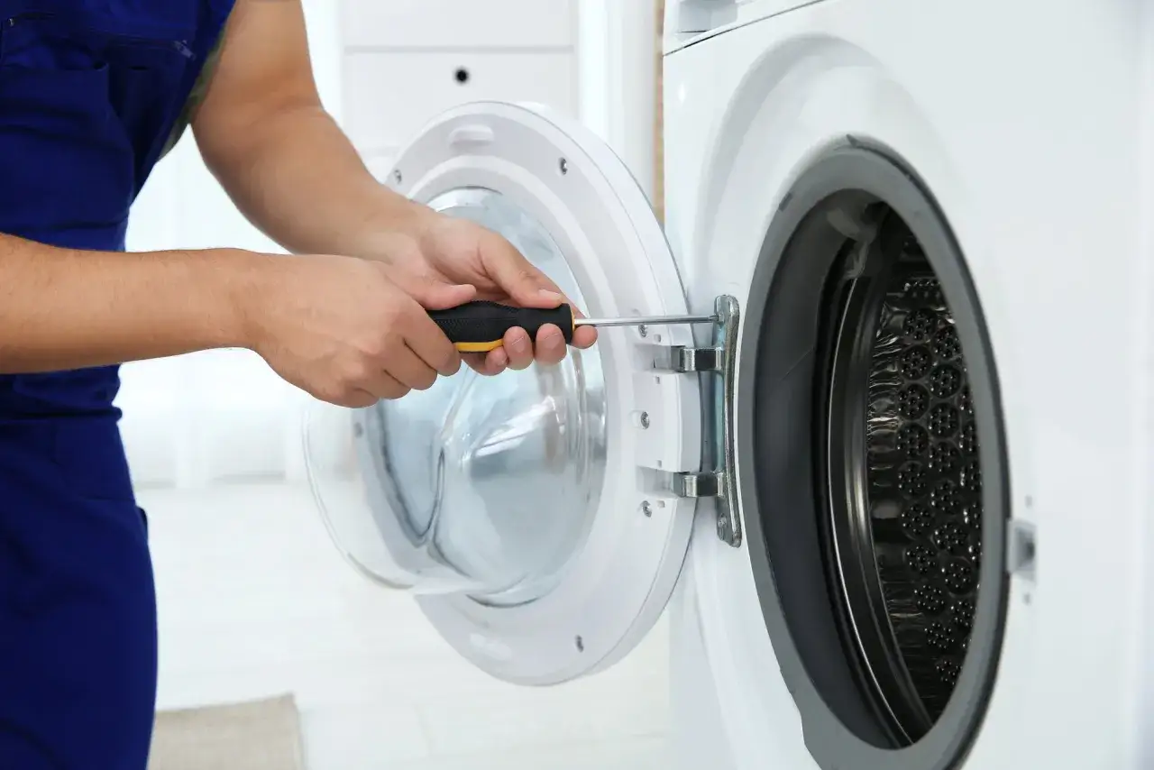 Monteur repareert de wasmachine. De wasmachinetrommel loopt aan, hij draait soepel na reparatie.