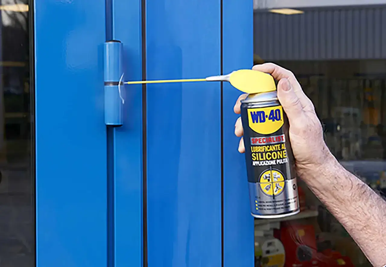 Hand spuit WD-40 op een blauw scharnier om het soepel te laten draaien. Dit is wat WD-40 doet: smeren en beschermen.