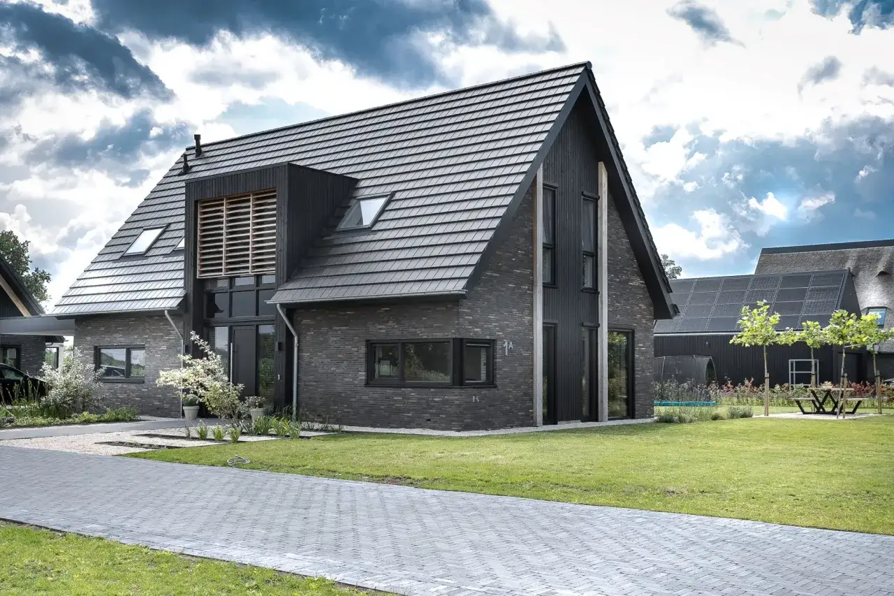 Moderne woning met donkere gevelstenen en houten accenten. Een kangoeroewoning is een woning die geschikt is voor dubbele bewoning, ideaal voor mantelzorg of een inwonend kind.