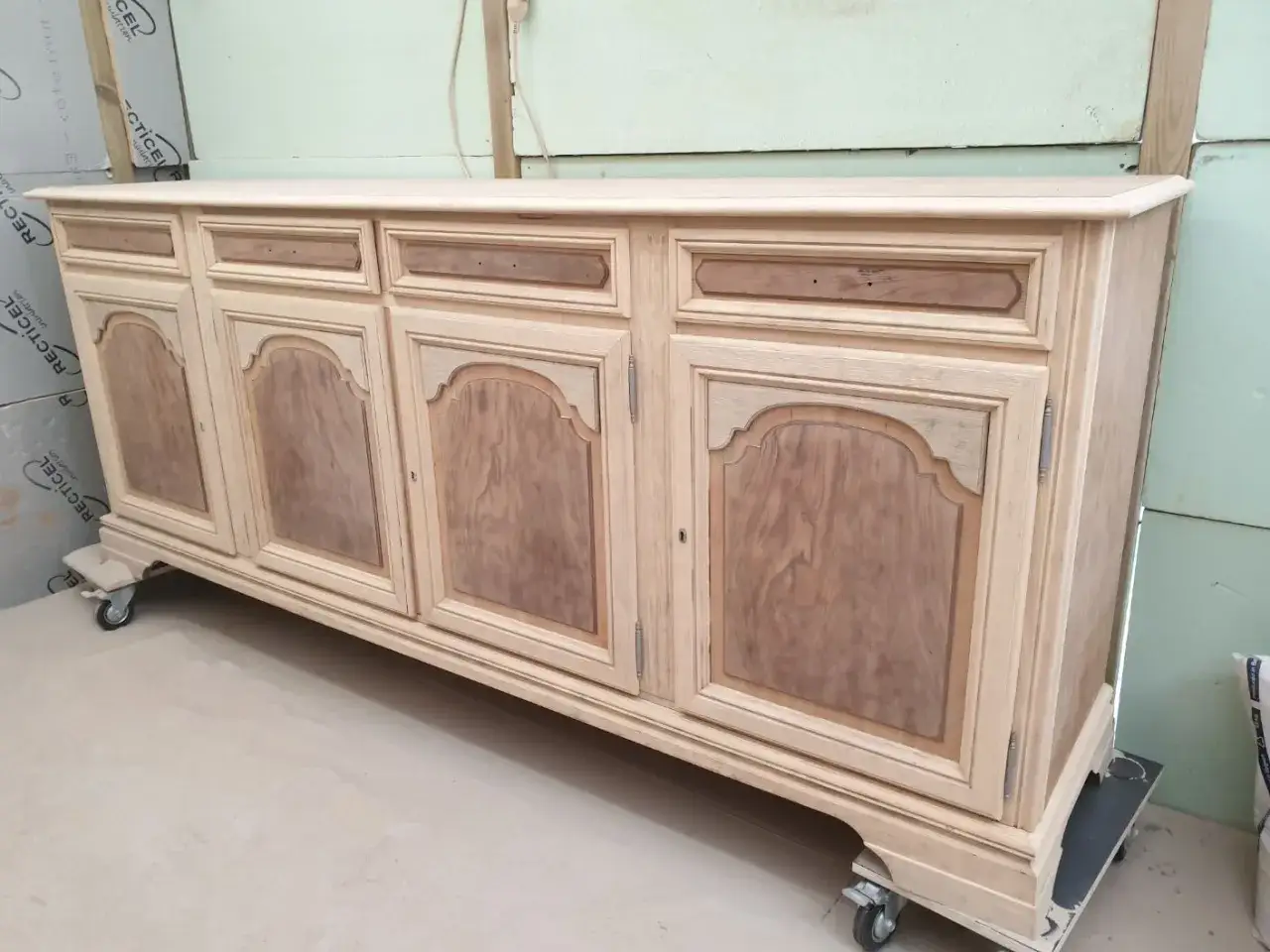 Buffet in de werkplaats, klaar voor meubels zandstralen. De lichte houtkleur en de details van de deuren zijn zichtbaar.