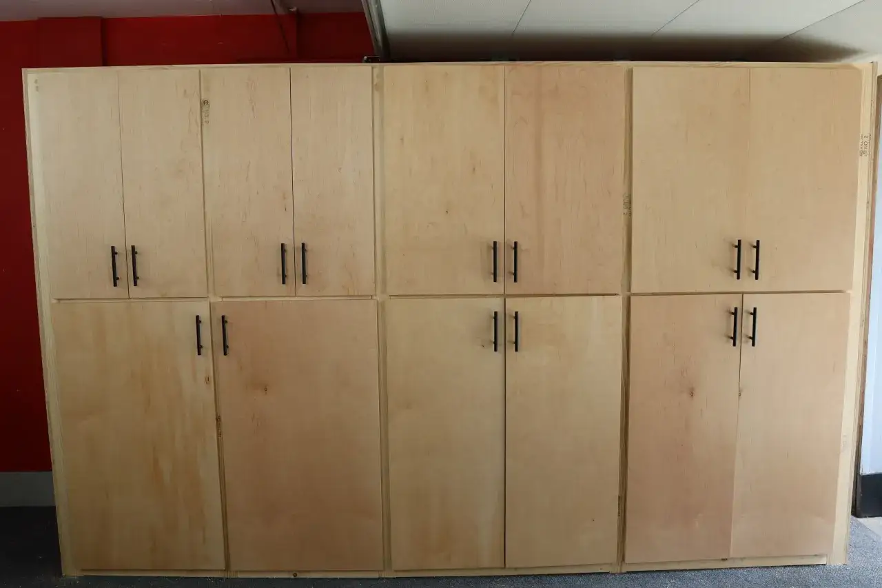 Een grote, lichte houten kast in de garage, ideaal om spullen op te bergen.