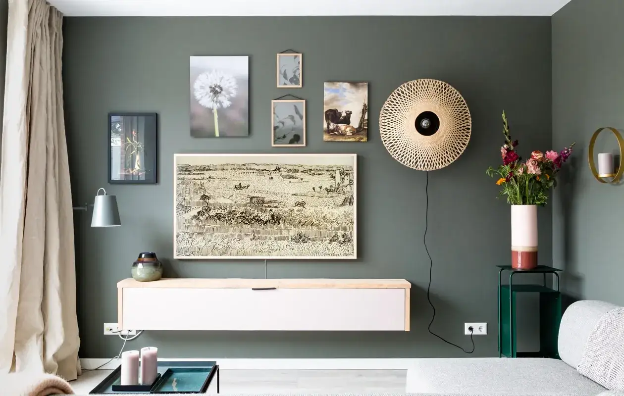 Een sfeervolle gallery wall maken met diverse kunstwerken, van een paardenbloem tot een landschapsschilderij.