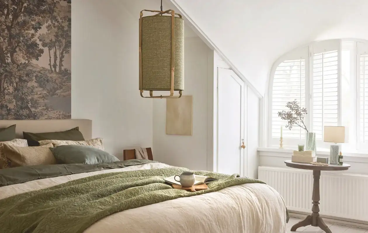 Rustieke slaapkamer verbouwen met groen beddengoed, een landschapswandkleed en een bijzondere lamp.
