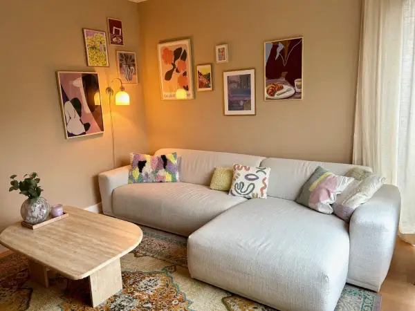 Een gezellige woonkamer met een lichte hoekbank, een salontafel en een inspirerende gallery wall maken.