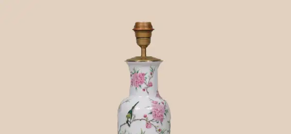 Een lamp maken van vaas: een witte vaas met roze bloemen en een vogel, omgebouwd tot lamp met een gouden fitting.