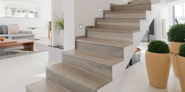 Moderne trap met houten look bekleding, perfect voor trap bekleden ideeen. Sfeervolle verlichting en planten maken het geheel af.