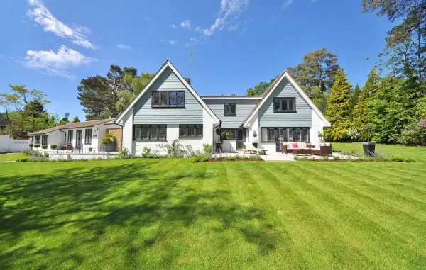 Een ruime woning met een aangebouwde garage, omringd door een perfect gemaaid gazon en bomen. Dit is een voorbeeld van wat een kangoeroewoning kan zijn: een woning met een apart woongedeelte.