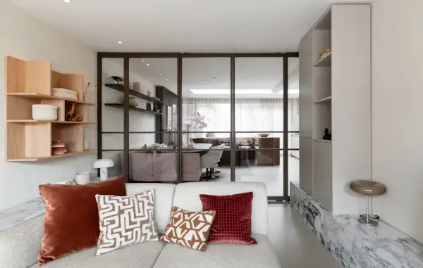 Moderne woonkamer met glazen wand, houten wandrek en comfortabele bank. Een nis in de muur is stijlvol ingericht.