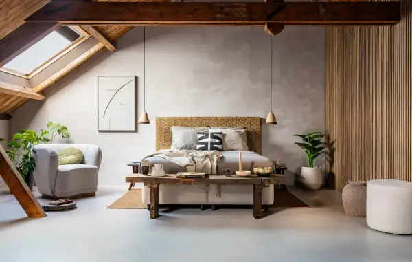 Slaapkamer met een bed, fauteuil, planten en een rustieke houten bank. De **plattegrond slaapkamer** toont een sfeervolle, lichte ruimte met een schuin dak.