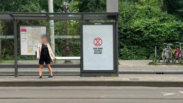 Een poster bij een bushalte met een symbool en de tekst "HIER HING FOSSIELE RECLAME". Dit is een oproep om geadresseerde reclame stopzetten.