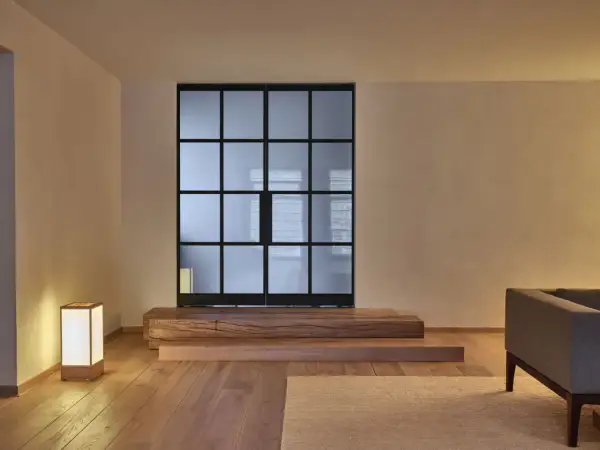 Een serene woonkamer met een glazen scheidingswand, houten elementen en een lamp, die de essentie van Japans minimalisme uitstraalt.