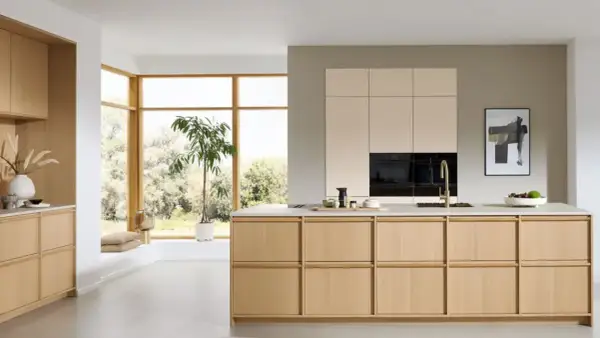 Een lichte, minimalistische keuken met houten kasten, een groot raam en een groene plant.