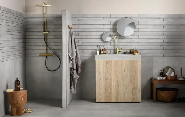 Grijze badkamer met houten meubel. Welke kleur handdoeken passen hierbij? Een grijze handdoek hangt aan de muur.