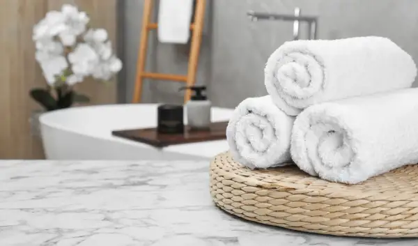 Frisse, witte handdoeken, net gewassen, liggen op een mandje in een luxe badkamer.