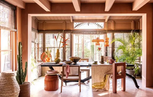 Warme, aardse tinten domineren deze eetkamer. De balken van het plafond zijn geschilderd in een lichte kleur, wat een mooi contrast vormt met de terracotta muren.
