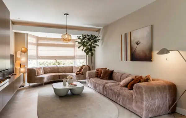 Een ruime, lichte woonkamer met comfortabele, roze banken en een bijzettafel. Dit is wat een vestibule kan zijn: een uitnodigende entree tot ontspanning.